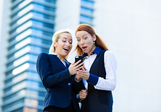 Surprised business women looking at smart phone, good news
