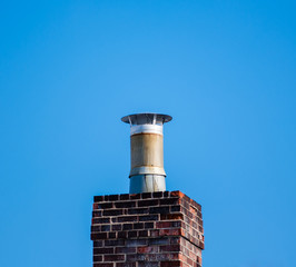 Dark brick chimney and filter on blue sky.