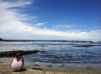 lonely girl sitting at sea shore