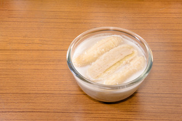 Obraz na płótnie Canvas Banana in coconut milk on wooden table,Thai traditional dessert