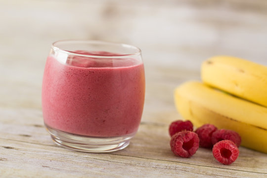 Banana Raspberry Smoothie in Clear Glass on Wood Backdrop