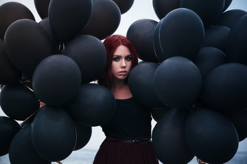 Obraz premium Beautiful girl walking with black balloons