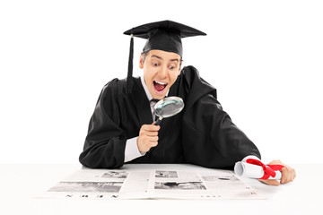 College graduate searching for job in newspaper