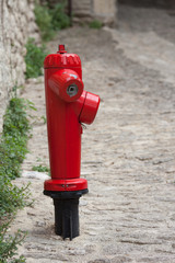 View of a red fire plug located on a street next in an old town