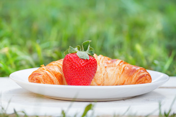 Plate with croissant and strawberry