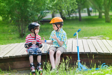 children with rollers and scooter sit on a wooden path