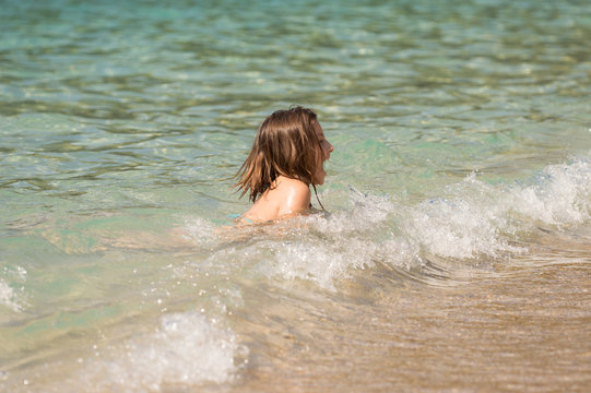Young Girl Playing on Waves In The Sea on Summer Holiday