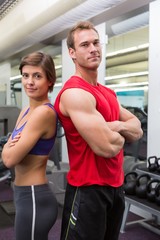 Fototapeta na wymiar Fit attractive couple smiling at camera with arms crossed