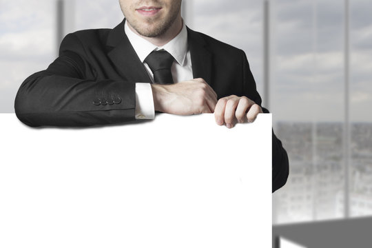 businessman leaning on blank sign