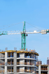 Crane and building construction site against blue sky