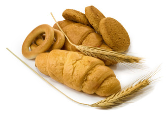 delicious bakery products and wheat on white background