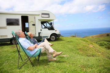 Senior couple relaxing in camping folding chairs, sea landscape
