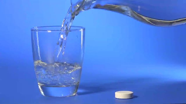dissolving aspirin tablets in a glass of water
