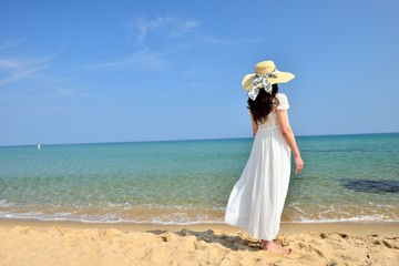 Fototapeta na wymiar 白いドレスを着て南の島のビーチに立っている黒い髪の女性