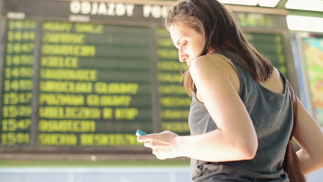 Woman looking at timetable departure board at train station