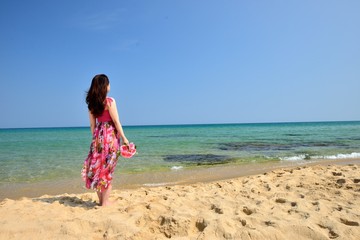 海を眺めるピンクのドレスを着た女性の後ろ姿