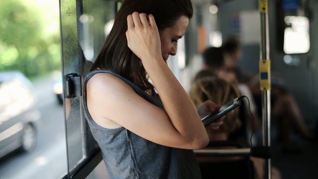 Woman listen to music on smartphone during tram ride
