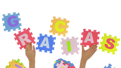 Hands forming word "Gracias" with jigsaw puzzle pieces isolated