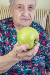 senior woman holding (giving) a fresh apple