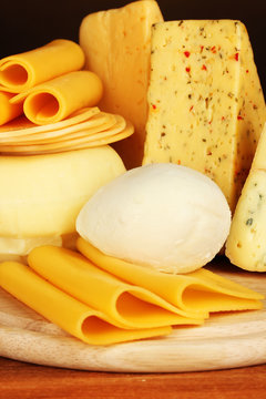 Various types of cheese on wooden board close up