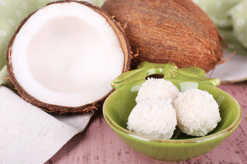 Broken coconut with candies on wooden background