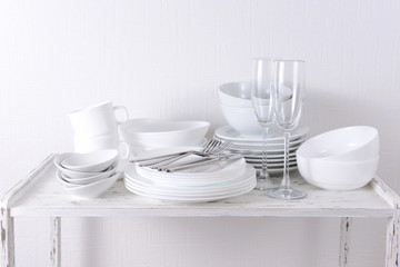 Set of white dishes on table on light background