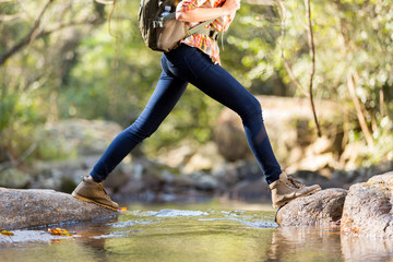 young hiker crossing stream in mountain