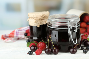Tasty jam with berries in glass jars on wooden table