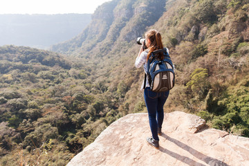 Obraz premium young woman taking photos on top of mountain