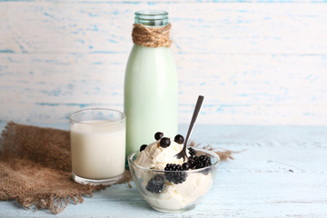 Glass bottle of milk and cottage cheese on wooden background