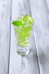 Green jelly with mint leaves in glass on wooden background