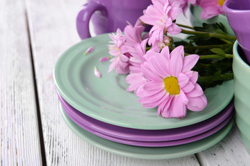 Cups and saucers with flowers on wooden background