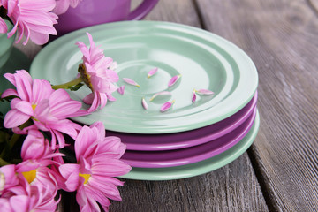 Obraz na płótnie Canvas Bright dishes with flowers on wooden background