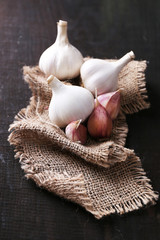 Garlic on sackcloth, on black wooden background