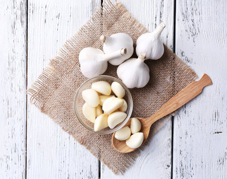 Fresh sliced garlic in glass bowl on wooden background