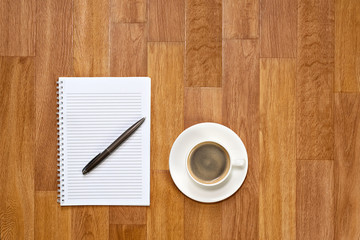 Blank notepad with office supplies and cup of coffee on wooden t