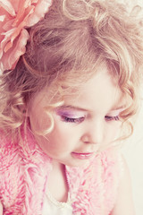 Fototapeta premium Beautiful young blond female child with curly hair posing in stu