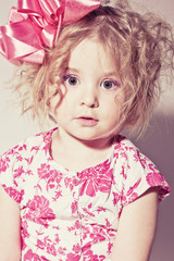 Beautiful young blond female child with curly hair posing in stu