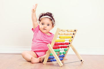 Baby girl sitting on floor and raising her hand