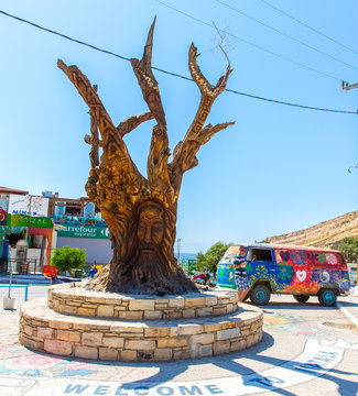 Tree with a carved face on the square in Matala, Greece Crete.