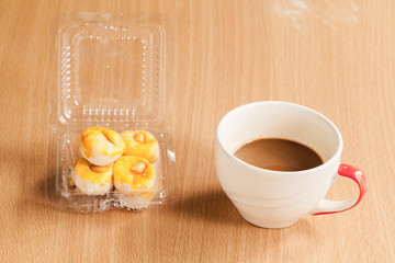 coffee cup with cookie on wood table.