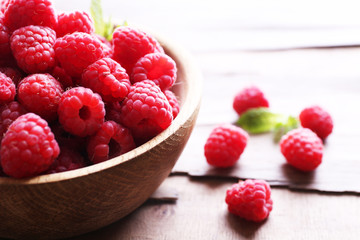 Ripe sweet raspberries in bowl on table close-up