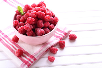 Ripe sweet raspberries in bowl on table close-up