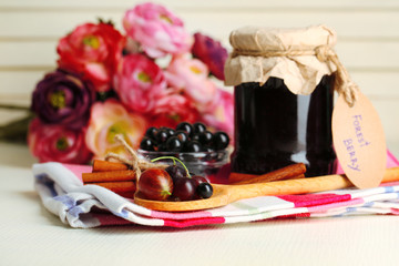 Obraz na płótnie Canvas Ripe blackcurrants in bowl and glass jar with tasty jam