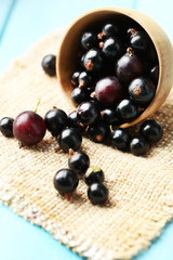 Ripe blackcurrants in bowl on wooden background.