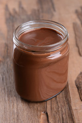 Sweet chocolate cream in jar on table close-up