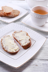 Fresh bread and homemade butter on plate on wooden background