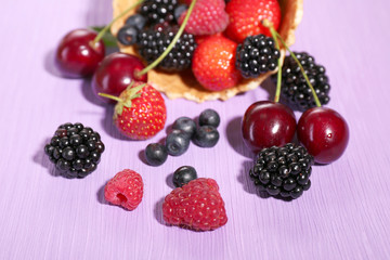 Obraz na płótnie Canvas Different ripe berries in sugar cone, on purple background