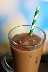 Glass of iced milk coffee on bright background