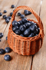 Delicious blueberries in wicker basket on table close-up